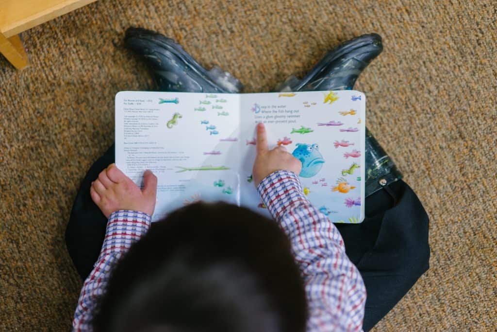 Criança lendo livro infantil